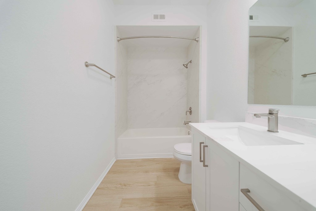 A white bathroom with a toilet, sink, and bathtub.