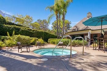 A pool surrounded by a patio with chairs and a table.