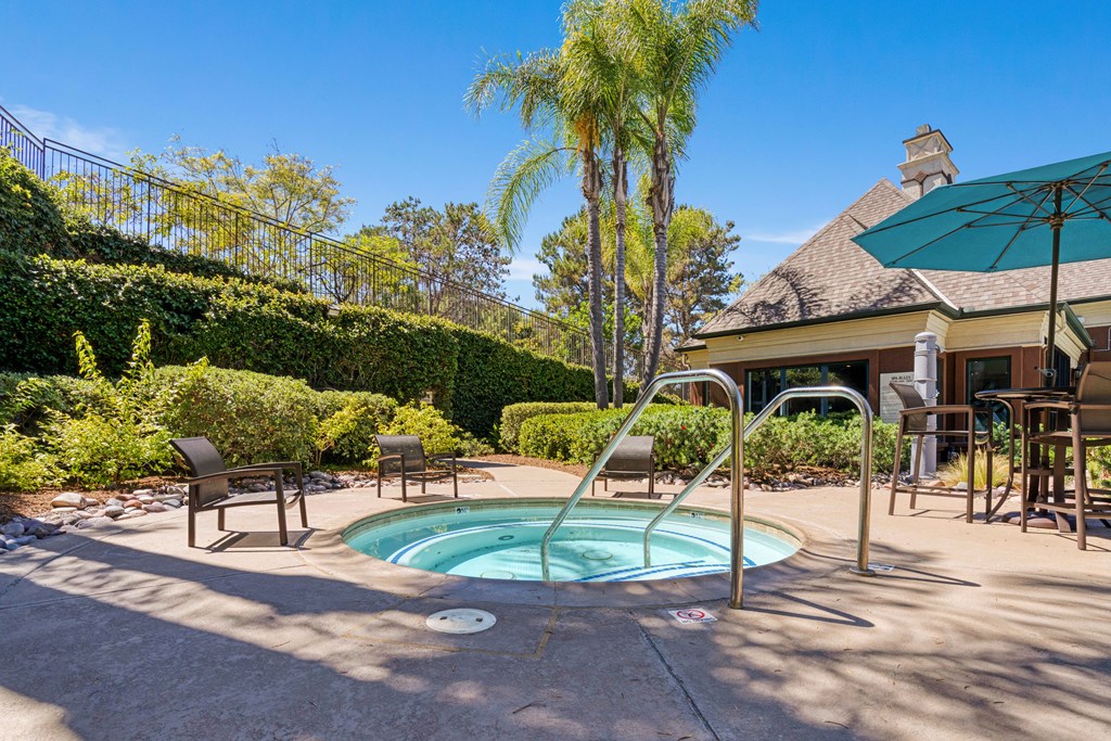 A pool surrounded by a patio with chairs and a table.