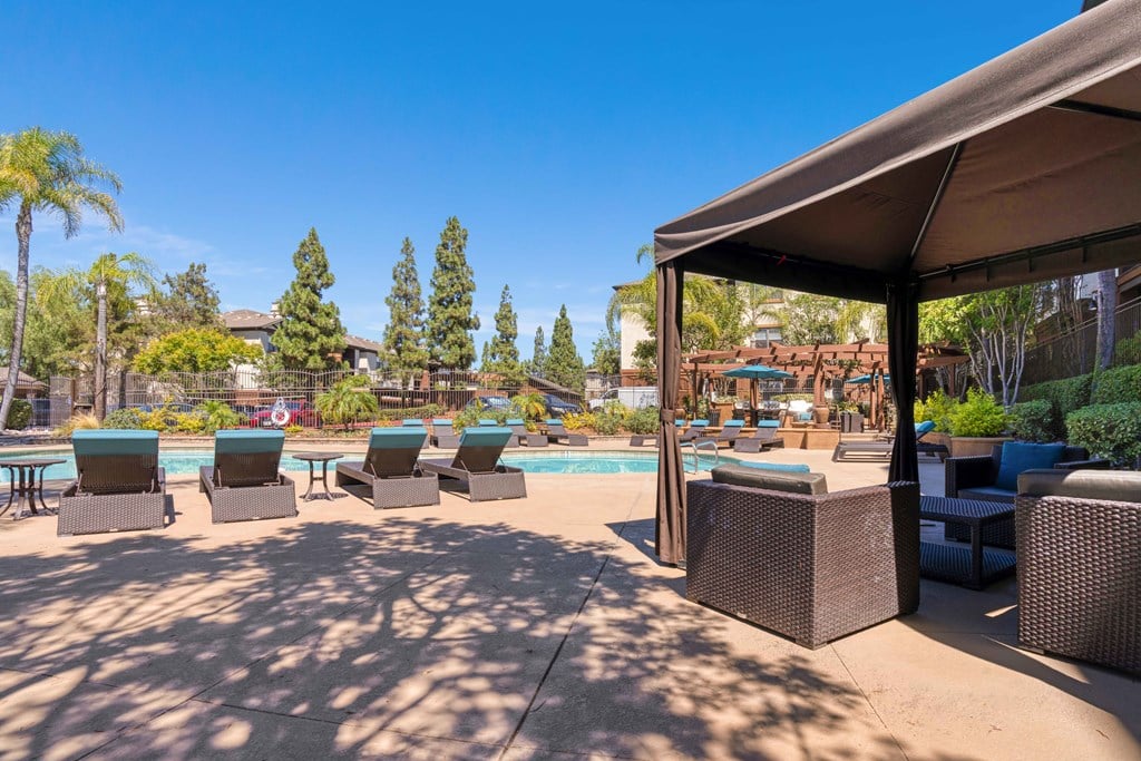 A poolside area with lounge chairs and a canopy.