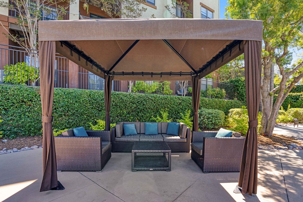A patio with a couch and a table under a canopy.