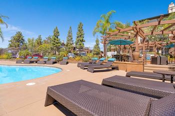 A pool area with sun loungers and a shaded seating area.