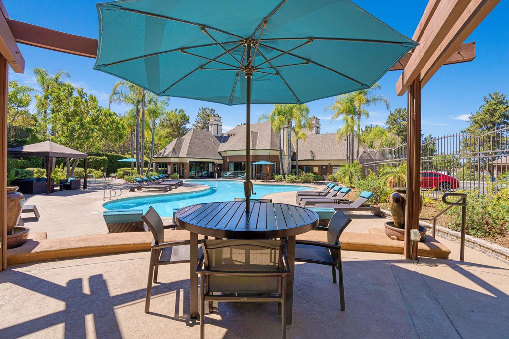 A patio with a table and chairs under an umbrella.