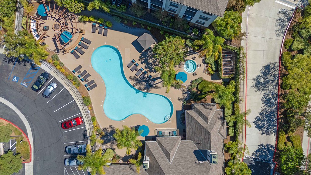 An aerial view of a swimming pool surrounded by trees and buildings.