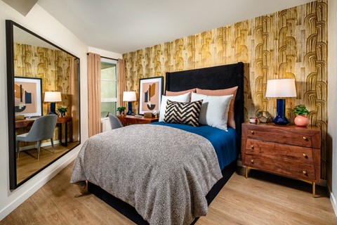 A bedroom with a large bed, a wooden nightstand, and a mirror on the wall.