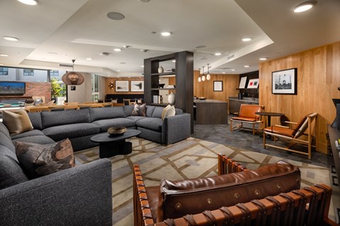 A living room with a grey couch and brown leather chairs.