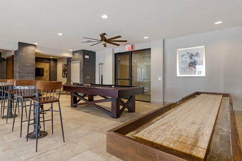 A room with a shuffleboard table and a pool table.
