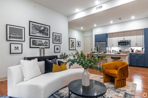 A living room with a white couch, a yellow chair, and a coffee table with a vase of flowers on it.