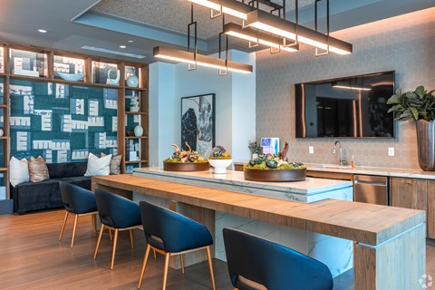 A modern kitchen with a long wooden island and blue chairs.