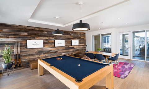 A pool table is in the middle of a room with a wooden wall.