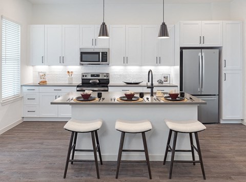 A kitchen with white cabinets and a grey refrigerator.