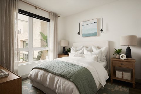 A bedroom with a large bed and a window with curtains.