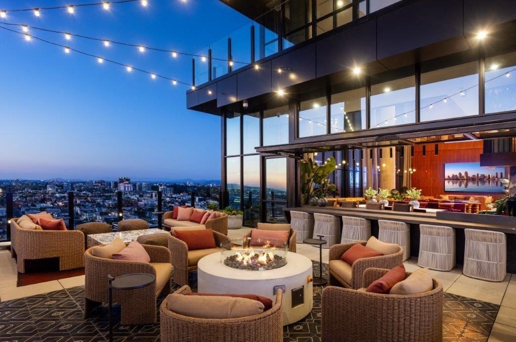 A rooftop patio with a fire pit and wicker chairs.