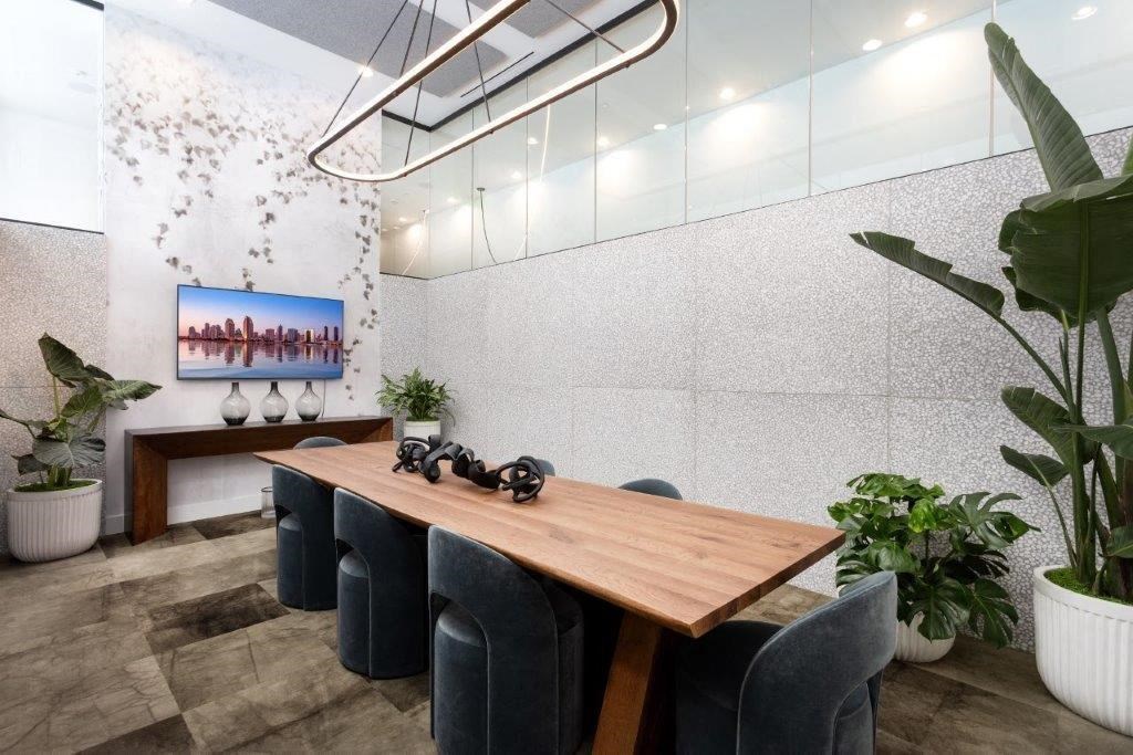A conference room with a long table, chairs, and a painting on the wall.