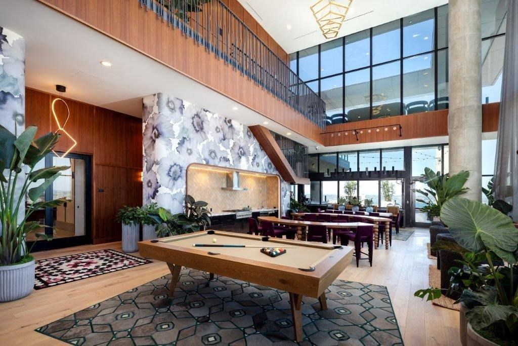 A billiard table is in the middle of a room with a wooden floor and a glass wall.