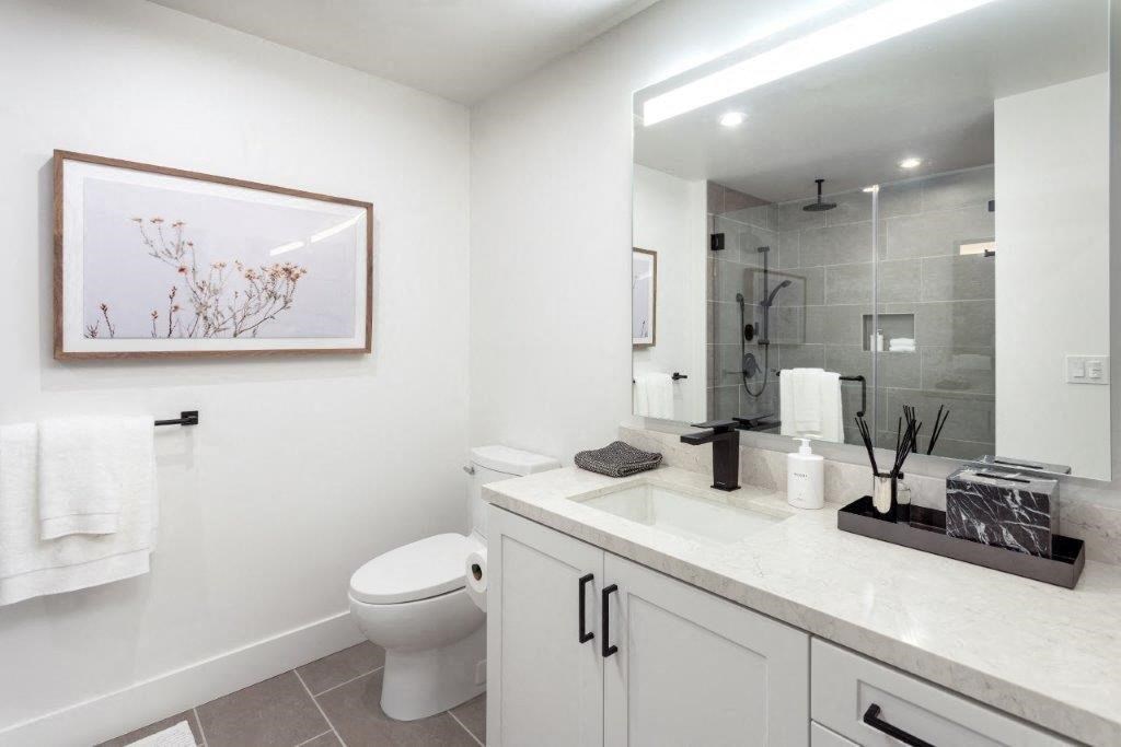 A bathroom with a toilet, sink, and a framed picture on the wall.
