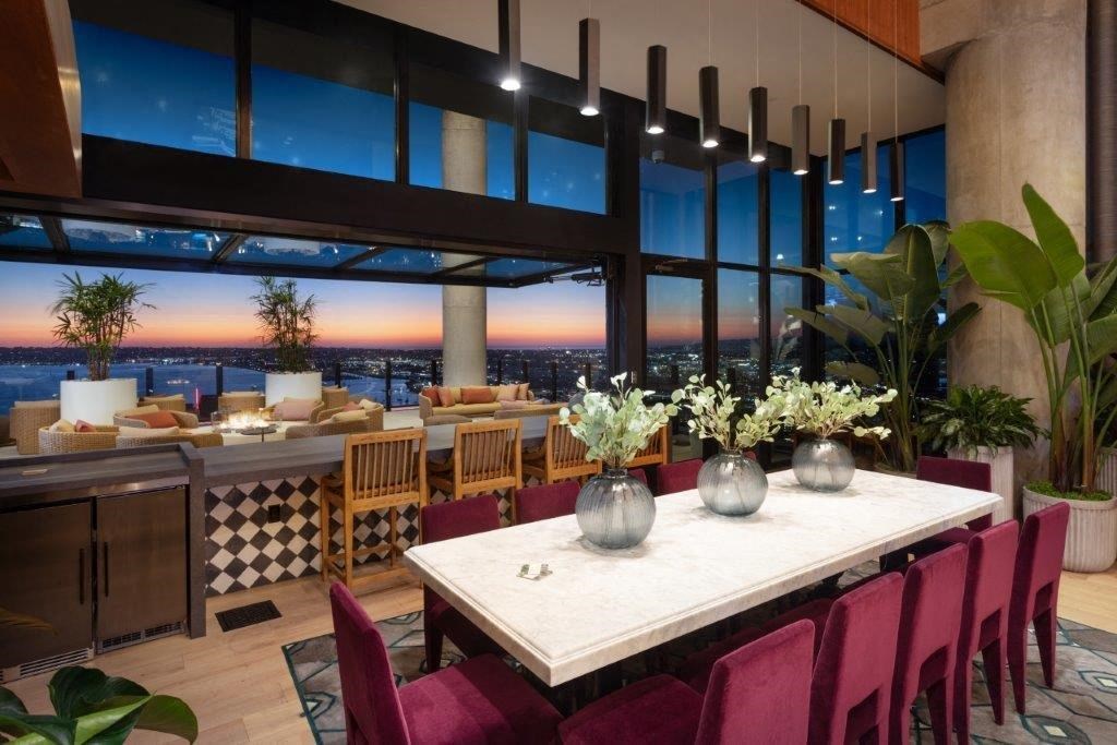 A dining room with a table set for six with a view of the city at sunset.