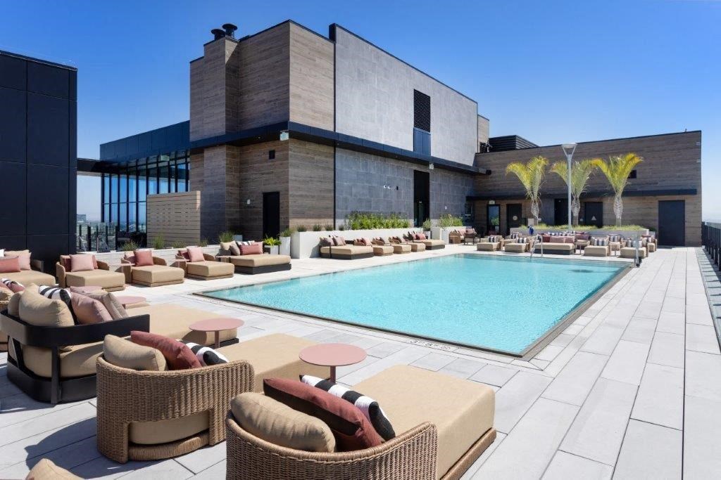 A modern outdoor pool area with wicker chairs and a glass wall.