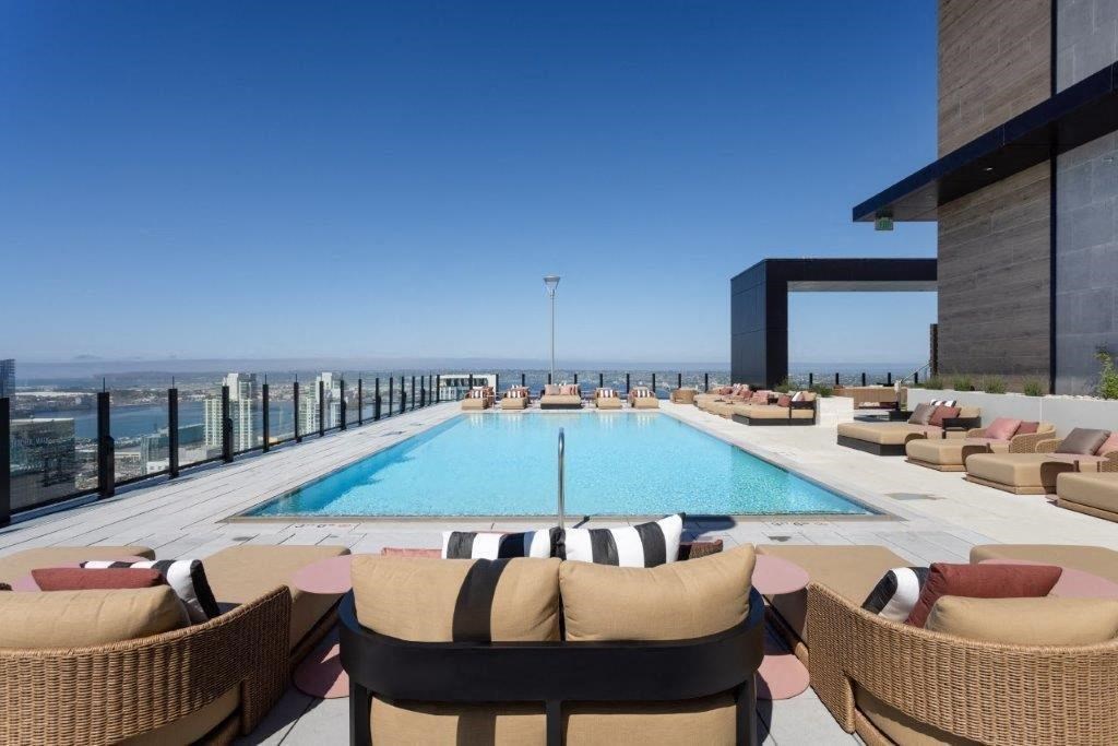 A pool surrounded by chairs on a patio.