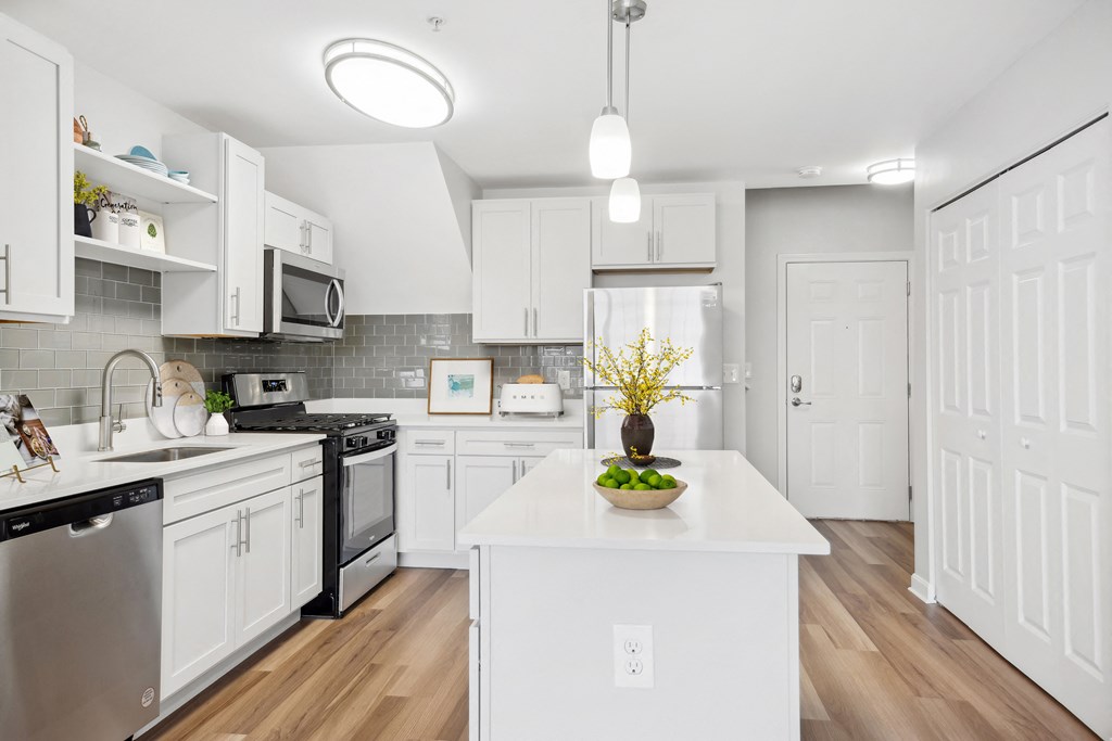 a large white kitchen with stainless steel appliances and white counters