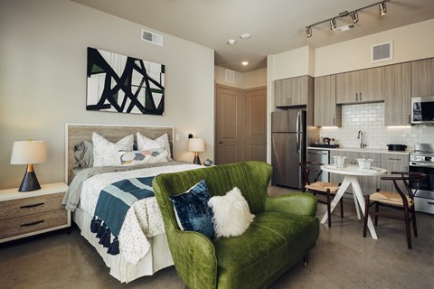 A modern bedroom with a green chair and a bed with a white comforter.