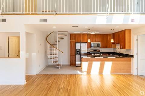 A modern kitchen with wooden cabinets and a spiral staircase.