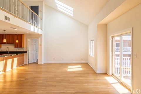 A spacious, empty room with wooden floors and a skylight.