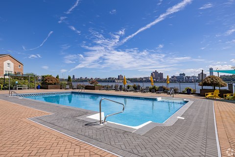 A large outdoor swimming pool with a tiled edge and a diving board.