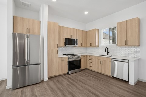 A kitchen with wooden cabinets and a stainless steel refrigerator.