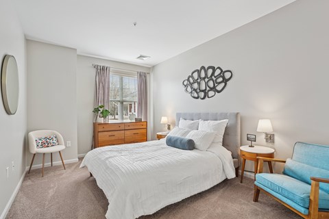A bedroom with a large bed, a chair, and a dresser.