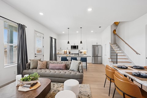 A modern living room with a grey sofa, a wooden coffee table, and a dining table set for four.