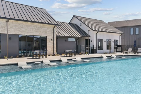 A swimming pool in front of a house with a black roof.