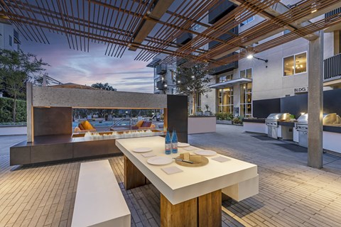 A modern outdoor dining area with a wooden table and benches.