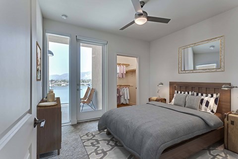 A bedroom with a large bed and a balcony with a view of the mountains.