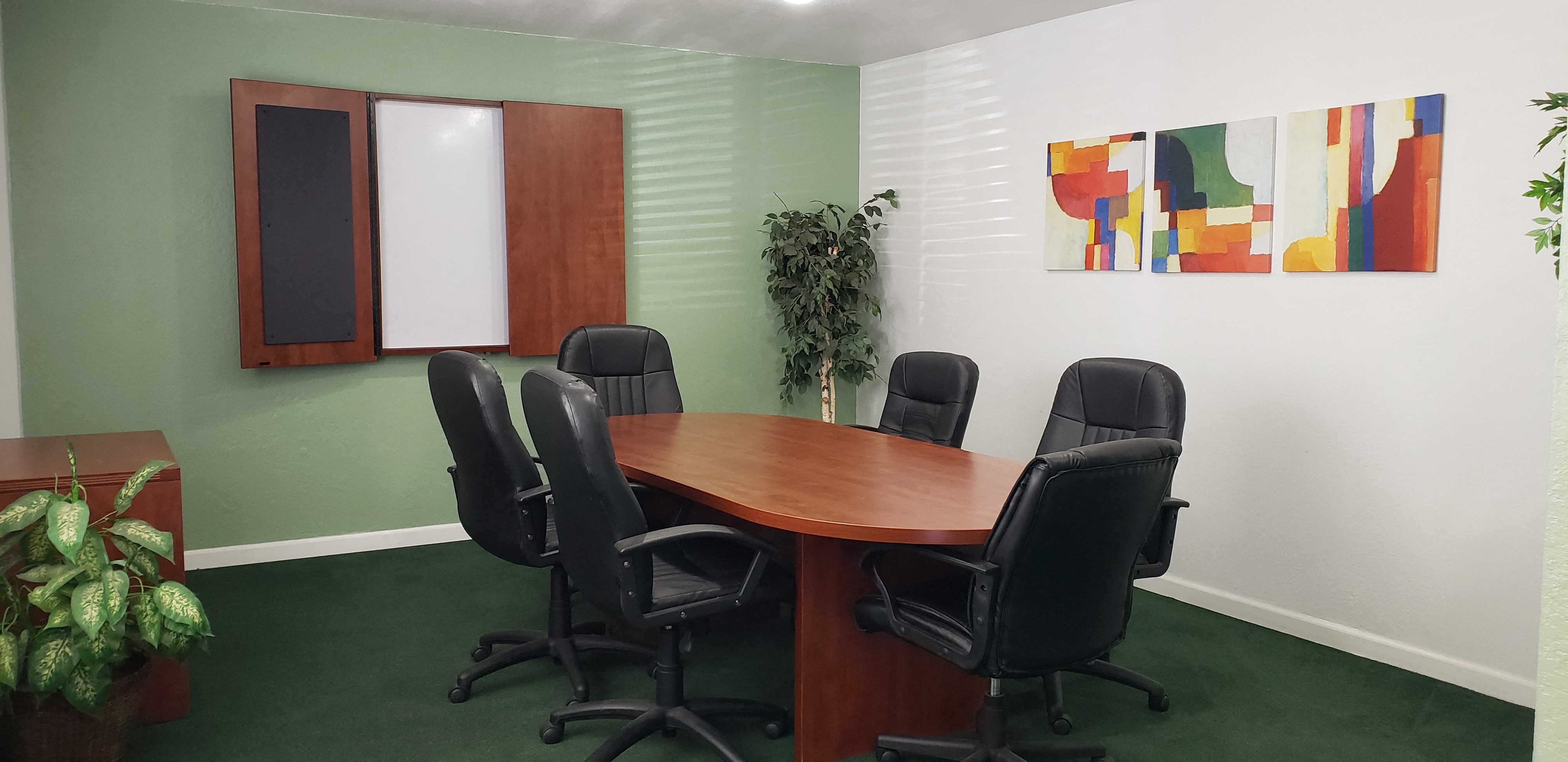 A conference room with a wooden table and six chairs.