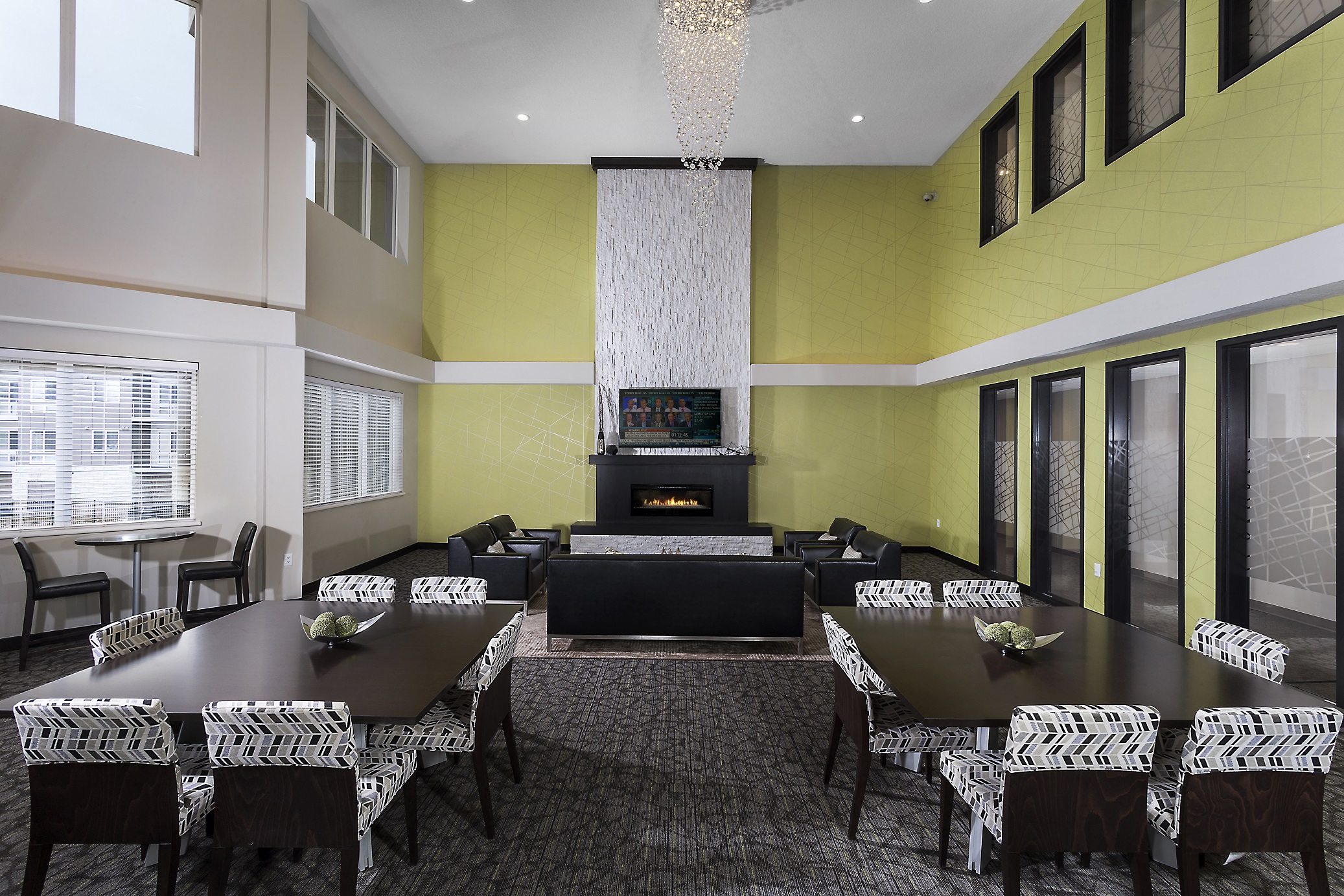 a clubroom with lots of different seating options, large tv, and chandelier