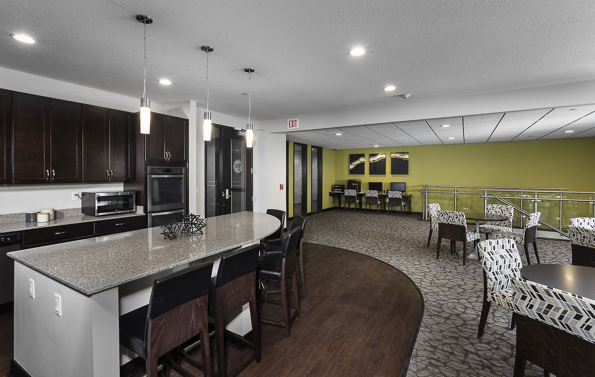 a business area with two desks and computers and a kitchenette area with high-top seating