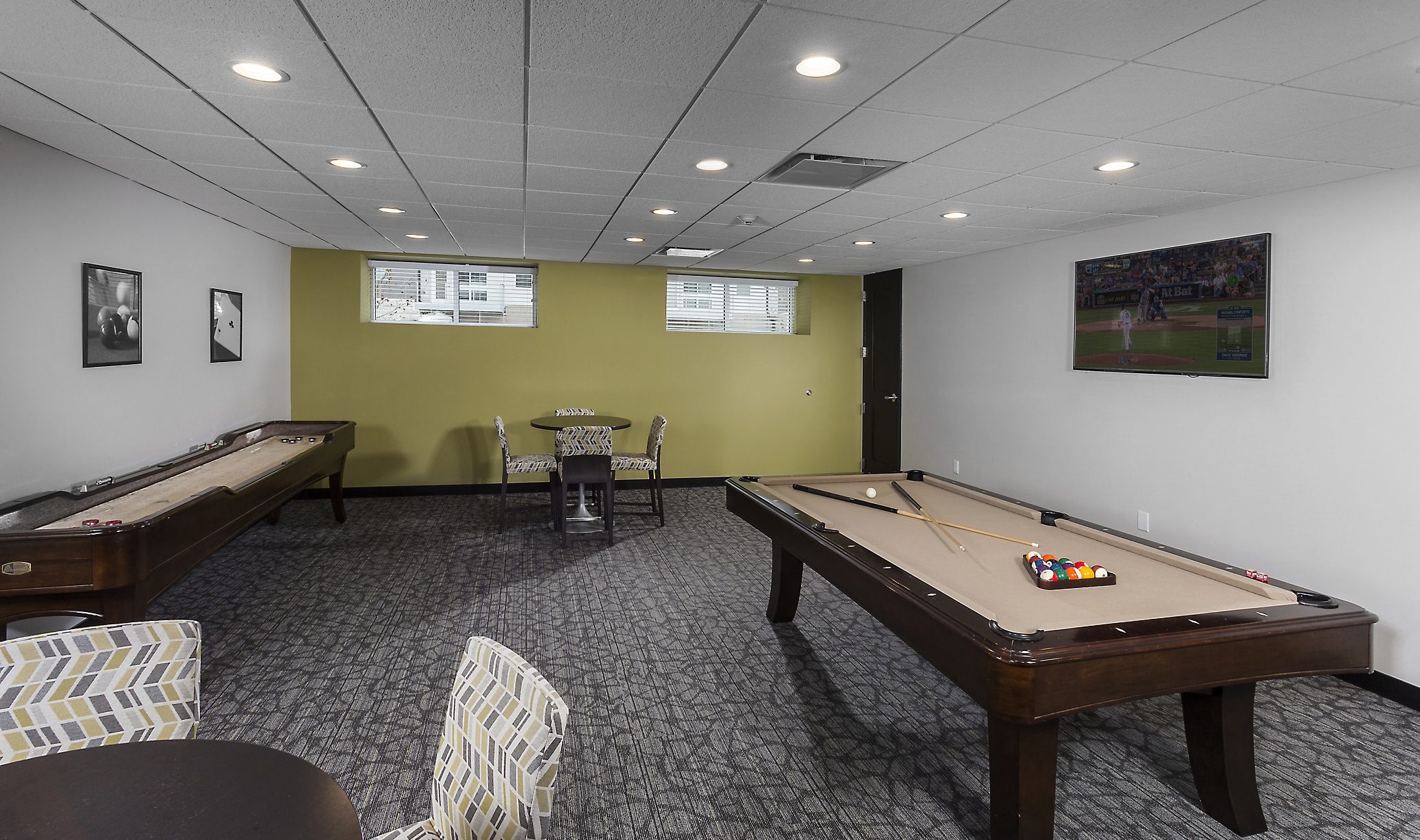 a game room with a shuffle board, seating, and games