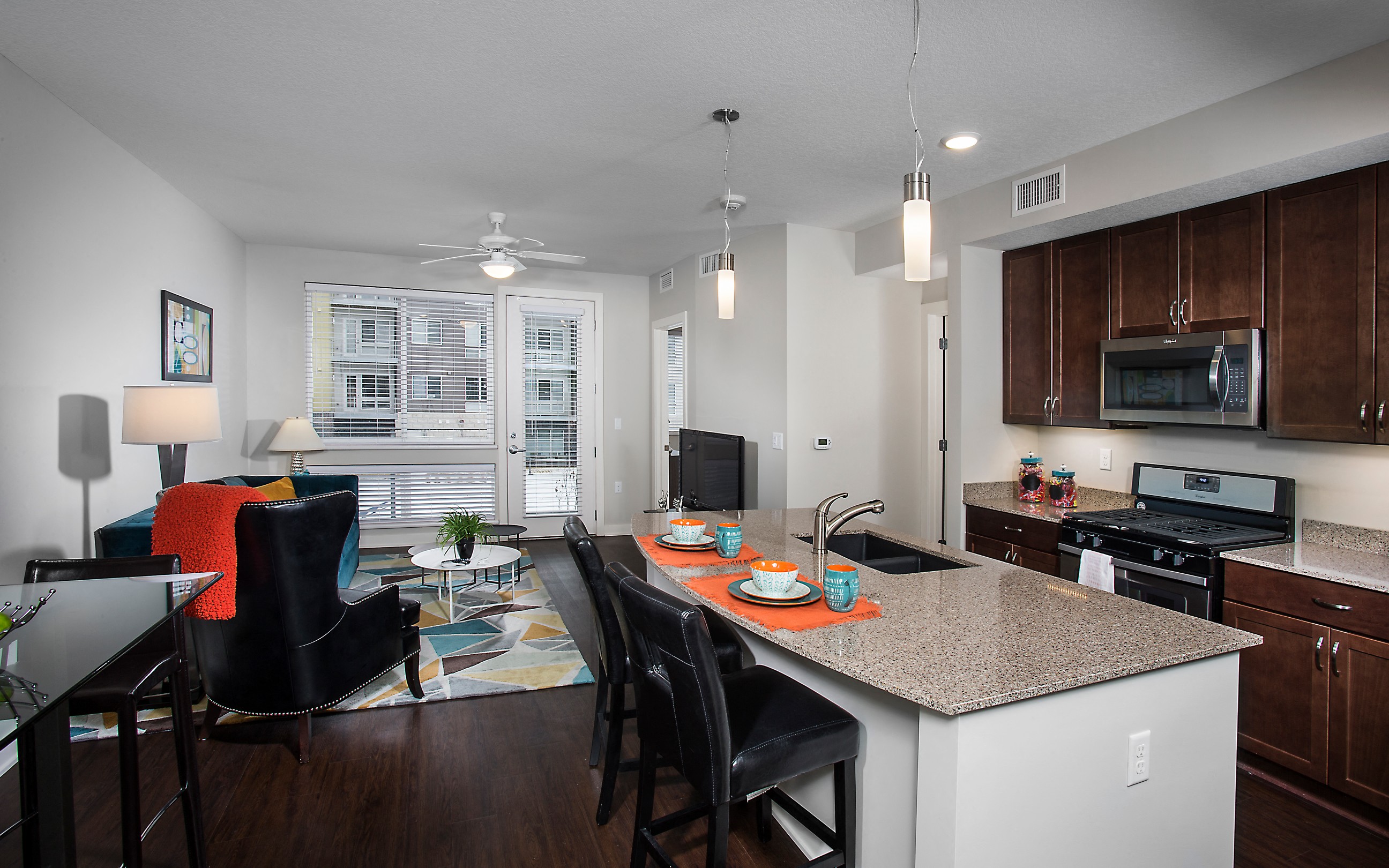 an open apartment space with large windows, an island and seating, and large windows