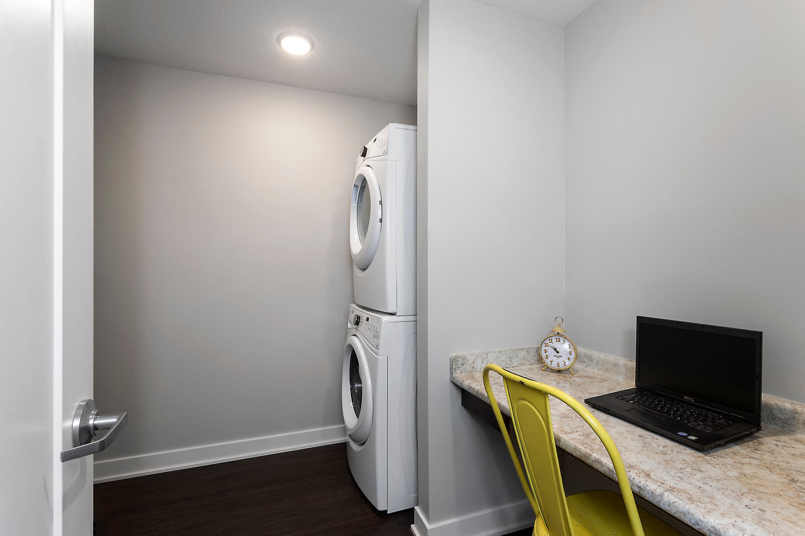 a stacked washer and dryer with a pocket desk nearby