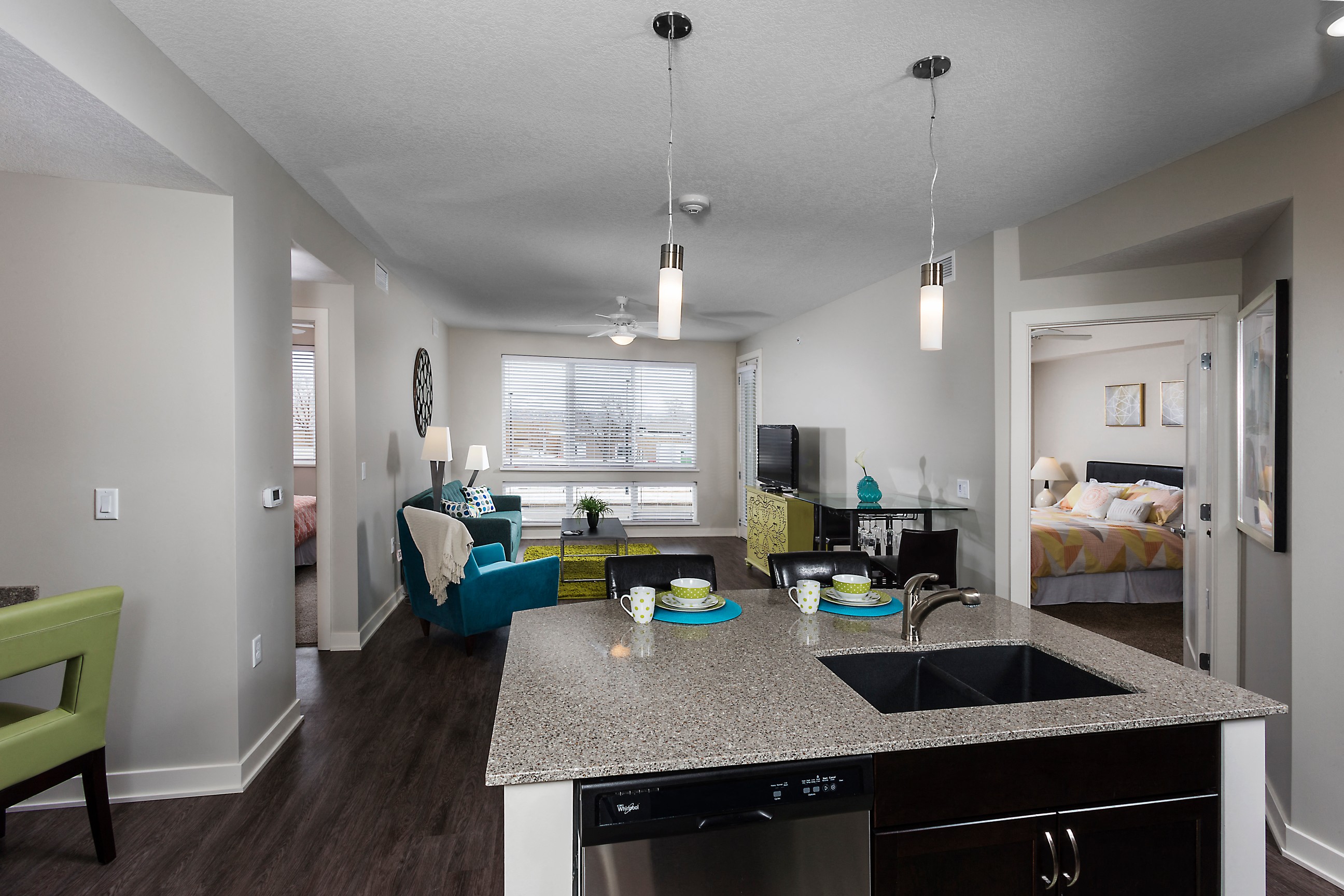 an open apartment layout with a sink, dishwasher, living space, and large windows