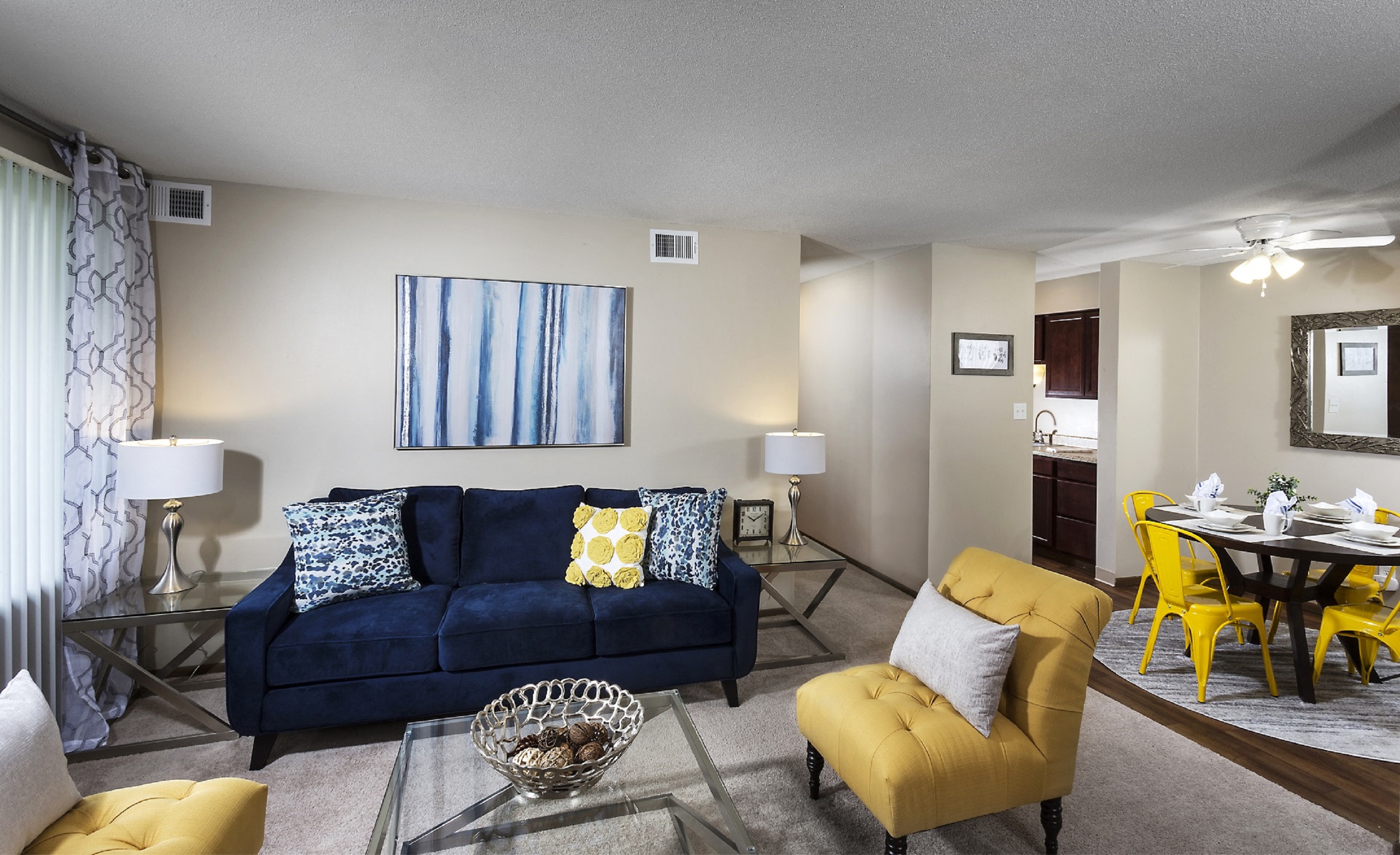 A living room with a blue couch and yellow chairs.