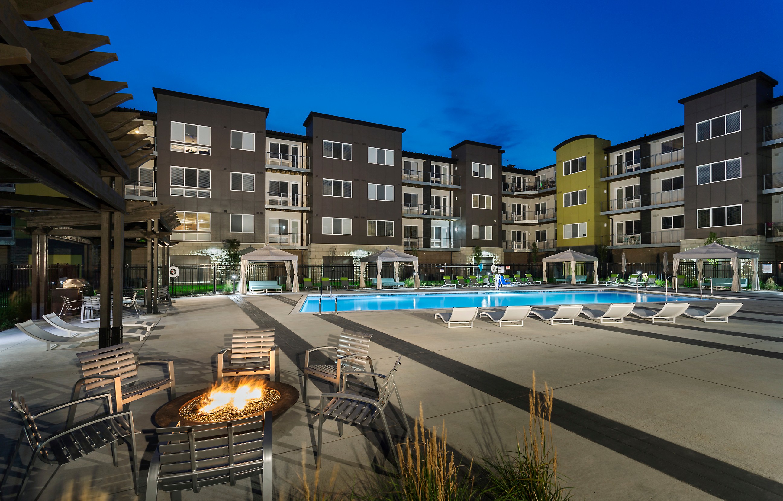 an exterior shot of the apartment community with a fireplace and seating and the heated saltwater, resort-style pool