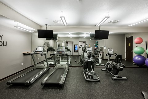 A gym with treadmills, exercise bikes, and a mirror.
