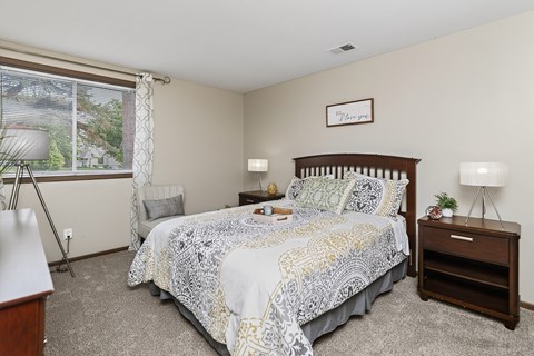 A bedroom with a bed, nightstand, and window.