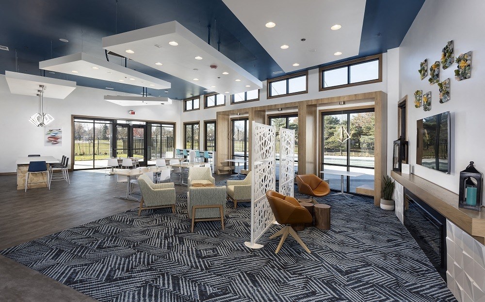 interior community room with comfortable seating and large windows overlooking pool