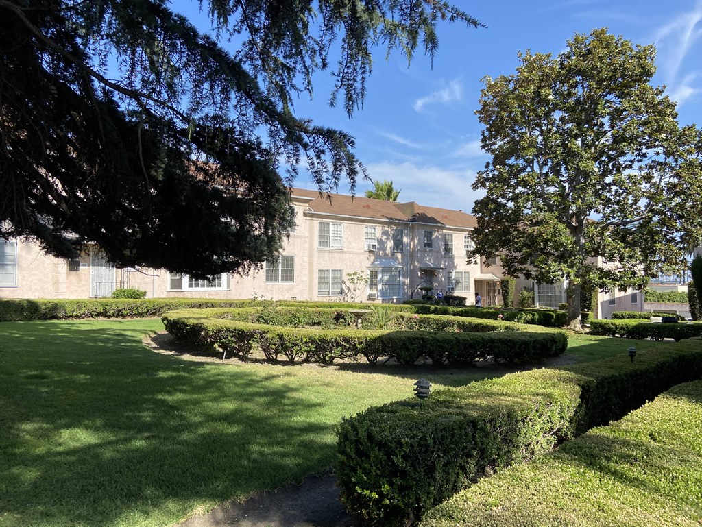 a large building with a lawn and hedges in front of it