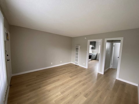 an empty living room with hardwood floors and grey walls