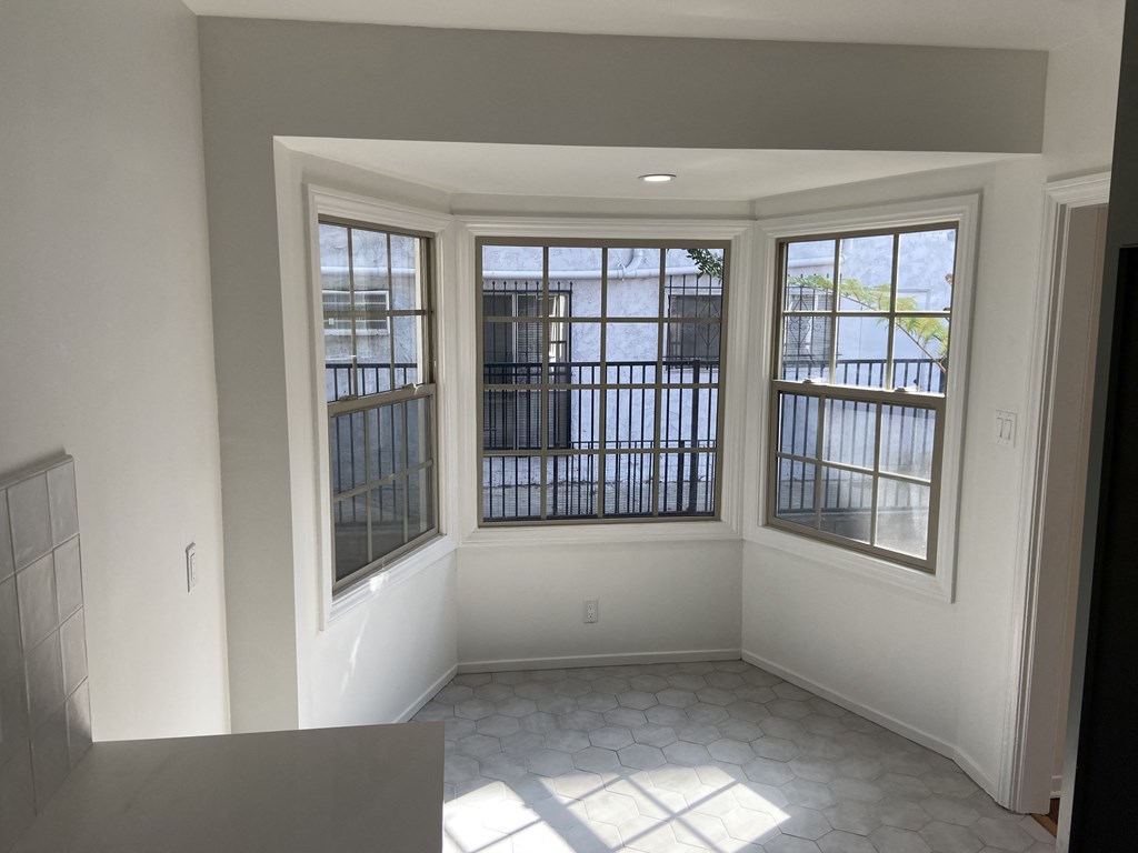 an empty living room with three windows and a tile floor