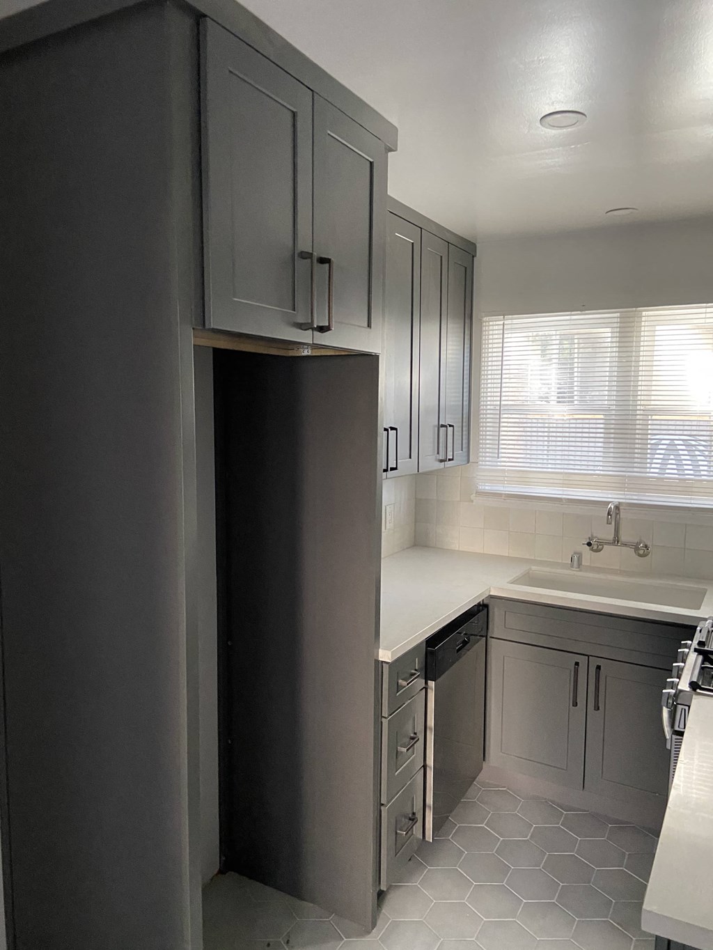 a small kitchen with white cabinets and a refrigerator